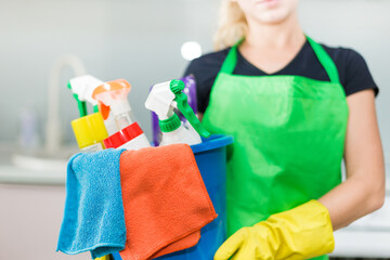 Young woman holding bucket with group of cleaning supplies for natural and environmentally friendly cleaning. Household equipment, tidying up, cleaning service concept, copy space