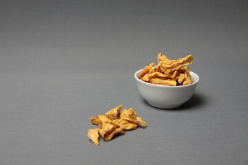 Healthy eating concept - a bowl of dried pineapple isolated on gray background
