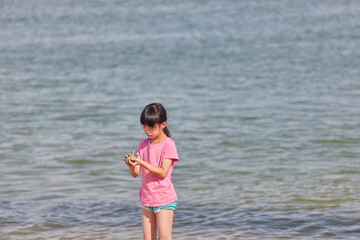 Fototapeta na wymiar 夏の海岸で海遊びしている小学生の女の子の姿