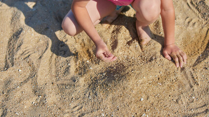 夏の海の海岸で砂遊びしている小学生の女の子の様子