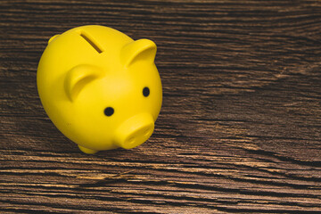 A cute yellow piggy bank about saving and investing, financial management and banking on the wooden...