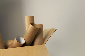 Heap used empty toilet paper roles made of recycled brown paper or cardboard in paper box against grey wall background with copy or negative space