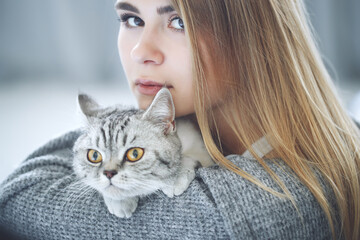 Beautiful young woman with a cute cat is resting at home. High quality photo.