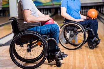 Two young disabled men in wheelchairs playing bowling in the club