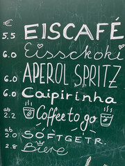 Kreidetafel mit Angeboten in einem Cafe, Eiscafé, Eisschoki, Aperol Spritz, Caipirinha, coffee to go.