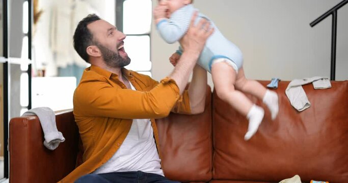 Happy father playing with newborn baby alone at home. Concept of happy fatherhood