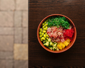 Hawaiian tuna poke bowl with vegetables on wooden table