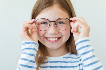 Health care, eyeball check, clear vision concept. Close up portrait of charming schoolgirl in red and purple glasses