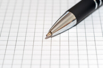 Ballpoint pen on the background of a sheet of checkered paper