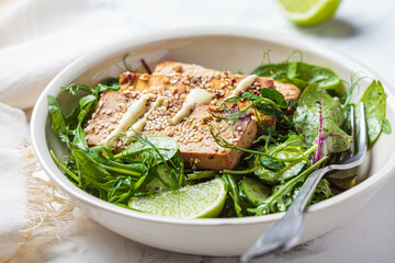 Fried tofu with green salad and nut dressing in white bowl. Asian cuisine, vegan food concept.