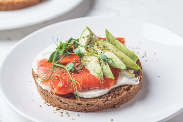 Breakfast toast with cream cheese, salmon and avocado, white background.