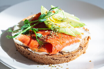 Breakfast toast with cream cheese, salmon and avocado, white background.