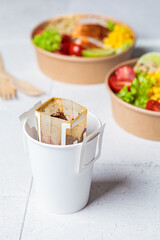 Making coffee with drip coffee bag in white paper cup.