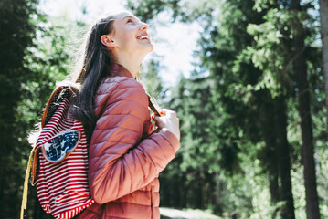 Pretty teen young tourist girl relaxing on forests road.Teenage with backpack on green forest...