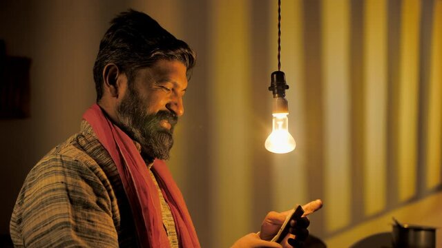 A happy village farmer counting his income - successful farmer from India. Medium shot of a handsome bearded farmer holding five hundred rupee notes - financial freedom 
