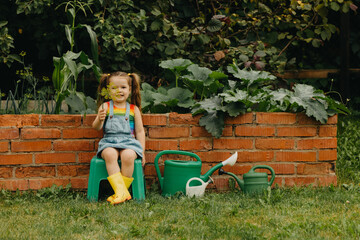 Little girl with watering cans in the garden.