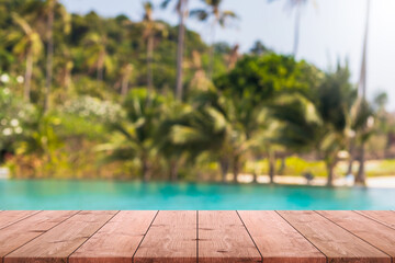 Empty wood table top and blurred swimming pool in tropical resort in summer banner background - can...