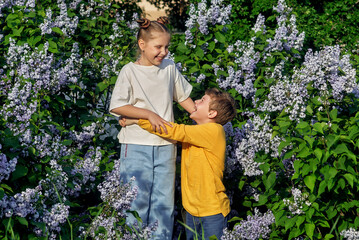 A boy and a girl on a walk on a summer day . Friends at the blooming lilac
