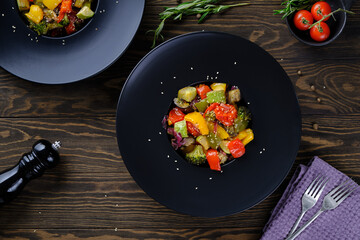 Delicious and useful food. Grilled vegetables on a round black plate on old wooden table