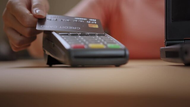 Close-up woman customer hand using credit card tap to pay on purchase machine to pay bill. Contactless and cashless technology  tap-and-go payment concept.