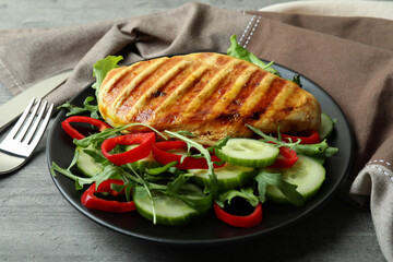 Salad with grilled chicken on gray textured table