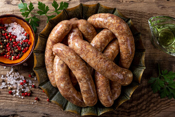 Raw meat sausages from beef and minced pork in a bowl and on wooden background top view close up