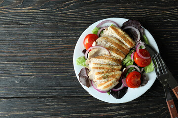 Salad with grilled chicken on wooden table