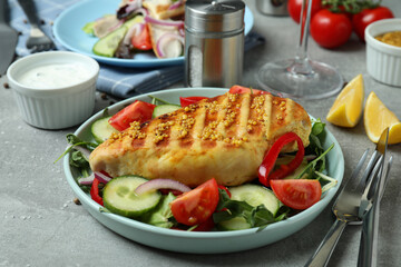 Concept of tasty eating with salad with grilled chicken on gray textured table