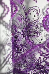Shadow of transparent curtain and floral patterns on the wall. Decorated purple fabric with intricate embroidery works. Wire, sequins and beads.