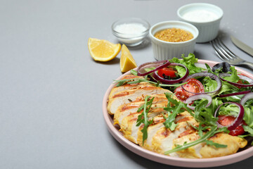 Concept of tasty eating with salad with grilled chicken on gray background
