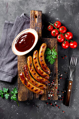  Grilled minced beef and pork sausages with barbecue sauce on wooden cutting board top view vertical photo