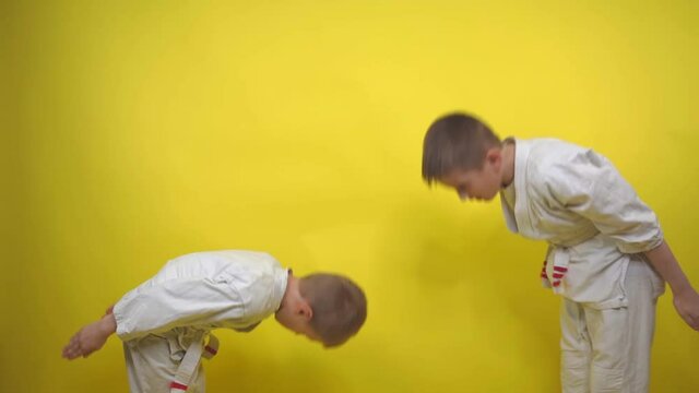 boys in kimono performs a greeting before starting a workout on a yellow background close-up, Ritsu Rei respect in sports sports, karate, aikido, judo, wushu, taekwondo Sports lifestyle. Martial Arts