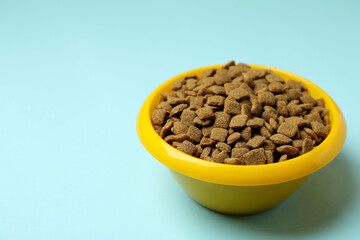 Pet bowl with feed on blue background