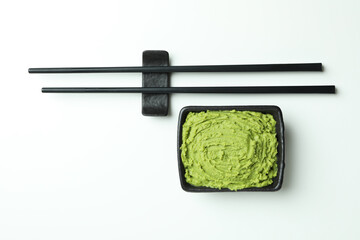 Chopsticks and wasabi sauce on white background