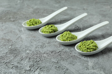Ceramic spoons with wasabi on gray textured background