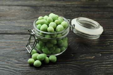 Glass jar with wasabi nuts on rustic wooden background