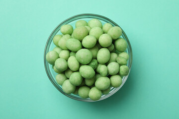 Bowl of wasabi nuts on mint background