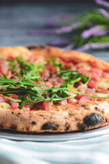 Pizza with salmon fish, cheese and fresh arugula over rustic gray wooden background. Italian cuisine concept