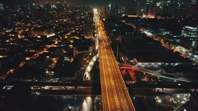 Slow motion night traffic road at twilight cityscape aerial. Urban junction overpass. Cars drive on highway. City panorama of business district. Neon lights of town streets. Madrid, Spain, Europe