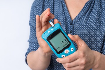 Woman is checking blood sugar level with glucose meter