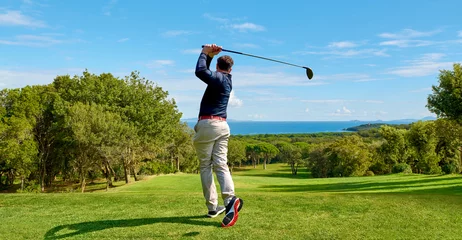 Tuinposter Golfer op de professionele golfbaan. Golfer met golfclub die de bal raakt voor het perfecte schot. © trattieritratti
