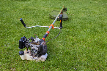 trimmer broken on the grass,Petrol trimmer disassembled on the grass
