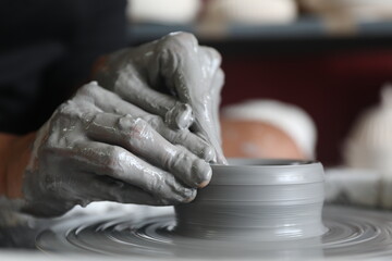 Hands of a potter at work, working on a pottery wheel.