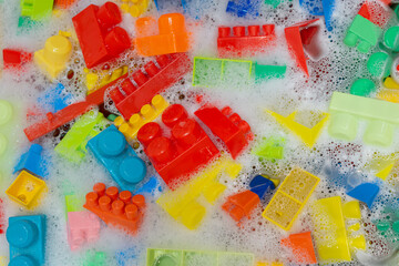 cleaning colorful toy building blocks. toys hygiene. washing plastic toys in bath with foam