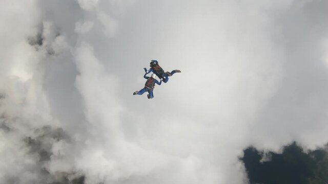 Skydiving. Two skydivers are falling near a big white cloud.