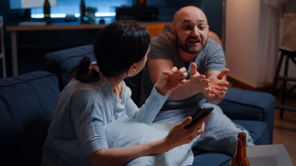 Helpless, frustrated, confused, desperate couple reading eviction notice from smartphone screaming at each other, fighting, arguing. Worried tenants by warning notification for unpaid bank bills