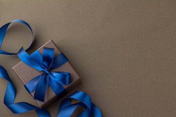 鮮やかな青いリボンとこげ茶色の背景のプレゼントのイメージ
