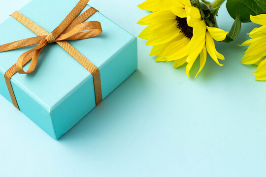 水色の背景と金色のリボンで結んだ水色の箱のプレゼントイメージ