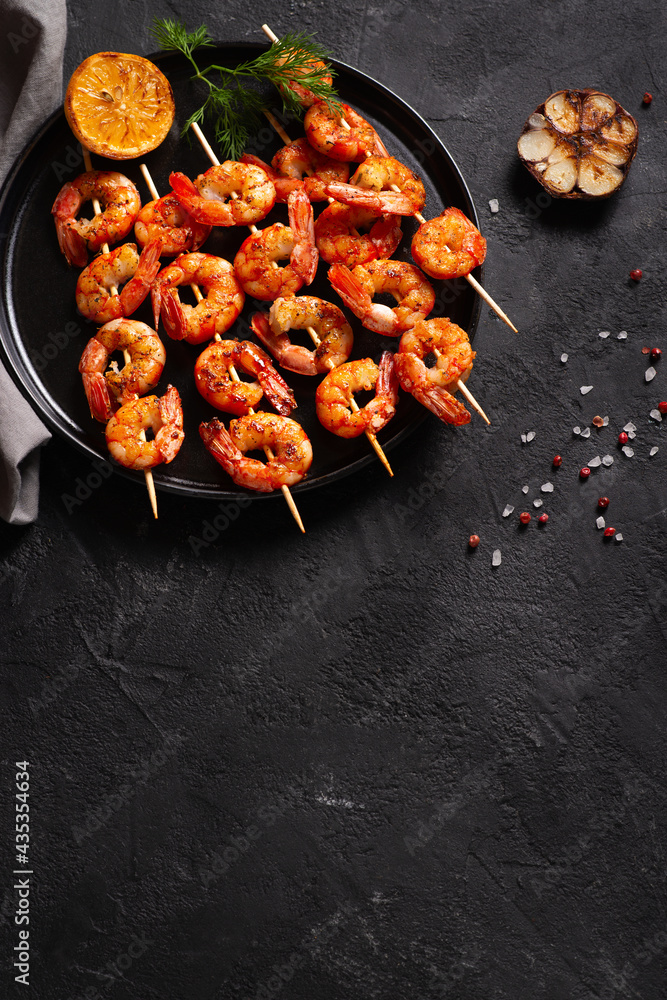 Wall mural grilled shrimp with garlic and lemon on black background