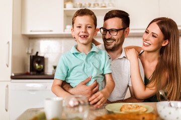 Obraz na płótnie Canvas Happy family having breakfast at home at the kitchen table.